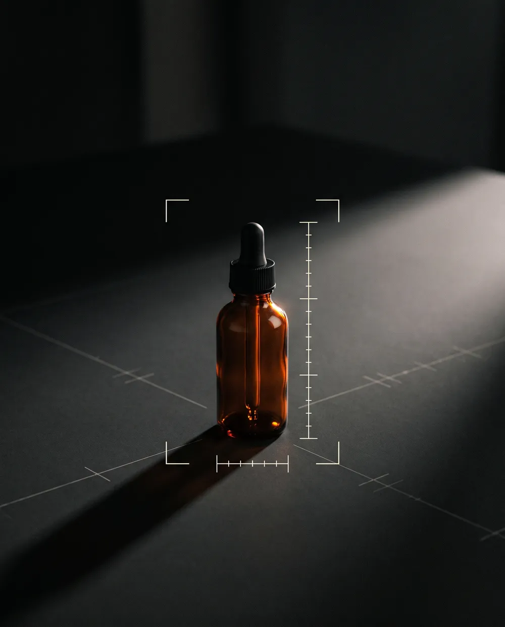 An amber dropper bottle inside crop marks on a dark floor